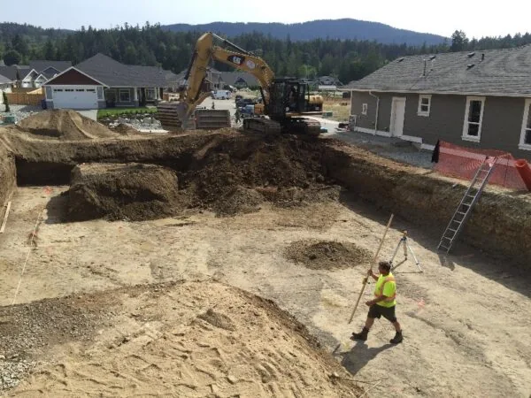 An excavator opening a foundation on a sloped lot