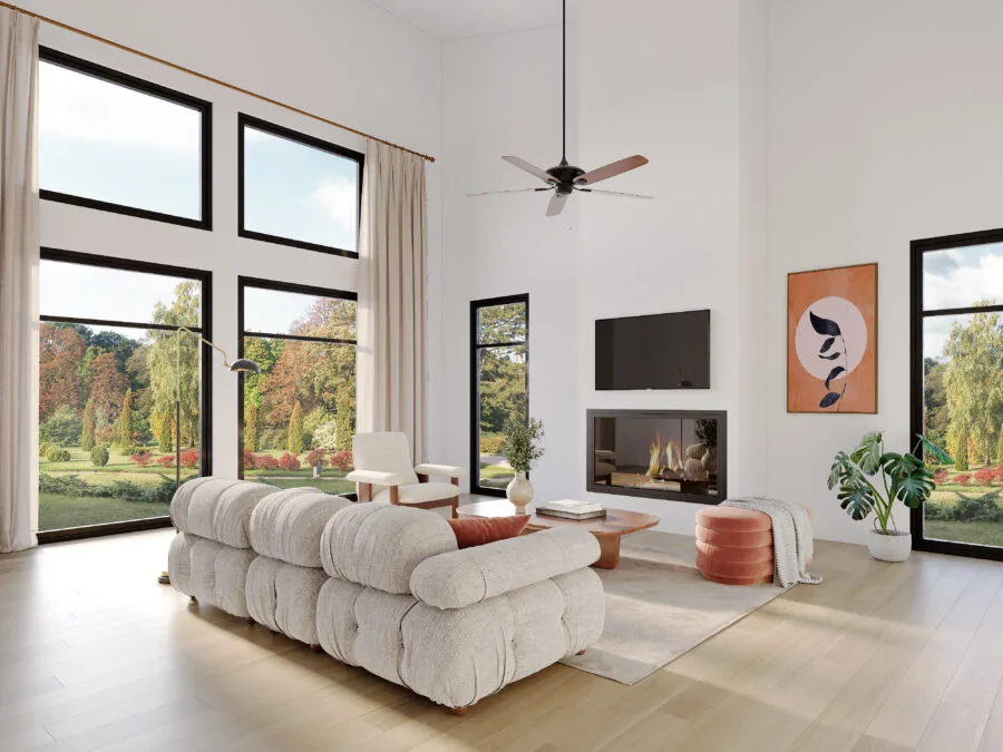 Modern living room with cream puffy sofa, fireplace, TV, ceiling fan, and expansive windows overlooking autumn forest. (2 of 4)