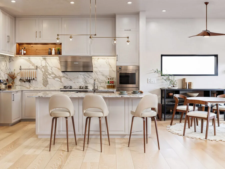 Modern open-concept kitchen and dining area with white cabinetry, marble backsplash, and wooden furniture. (4 of 5)
