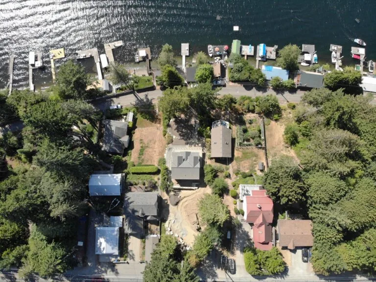 Aerial view of waterfront residential community with homes nestled among trees along a shoreline.