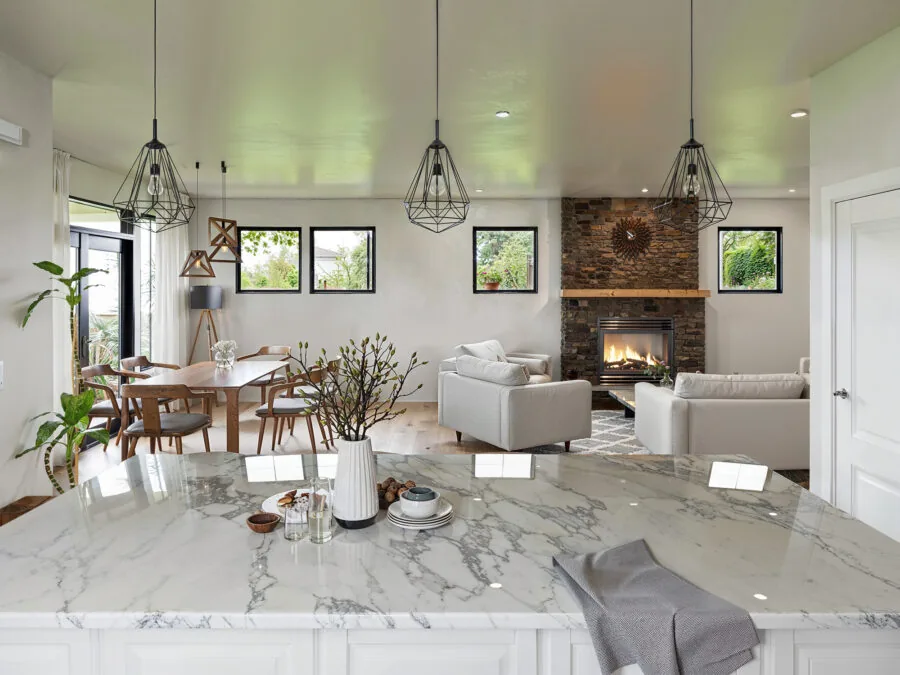 Modern open-concept home with marble kitchen island, fireplace, dining area, and living room with pendant lighting. (4 of 5)