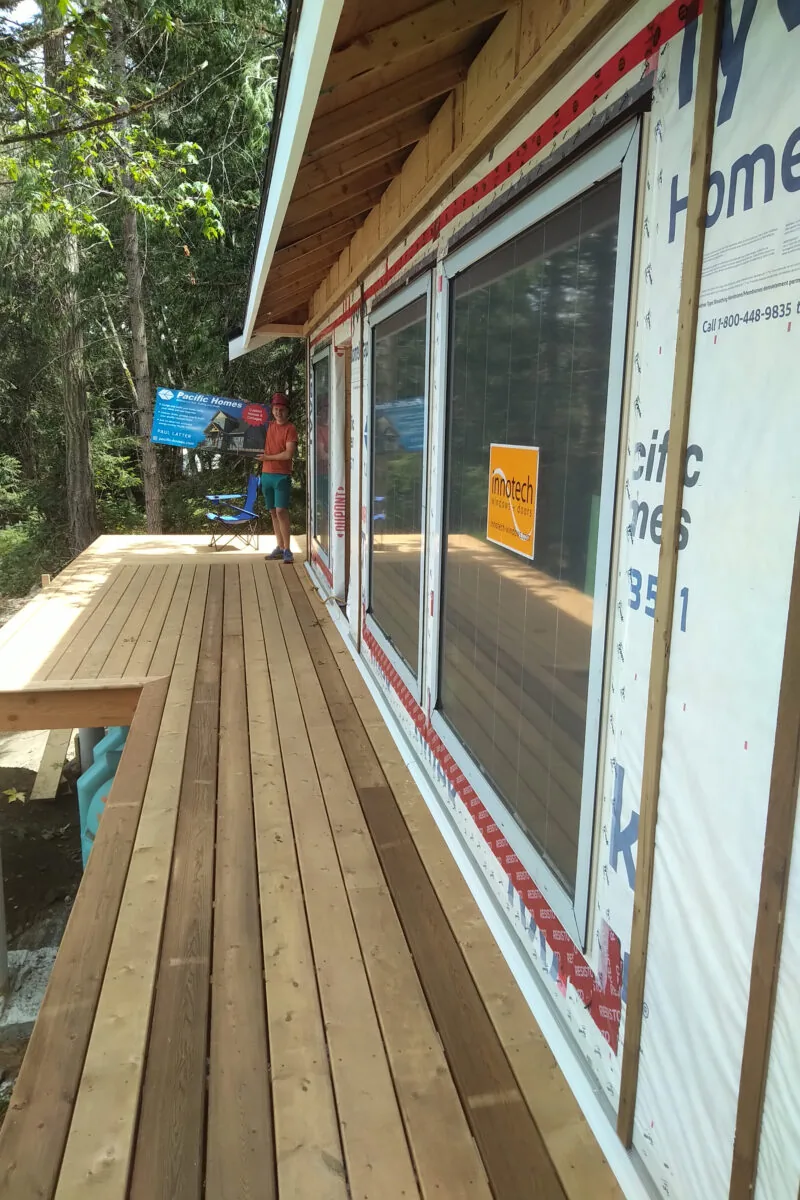 Construction deck with large windows and weatherproofing materials on a residential building under development.