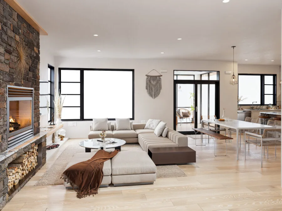 Modern open-concept living room with sectional sofa, fireplace, large windows, and dining area in neutral tones. (2 of 4)